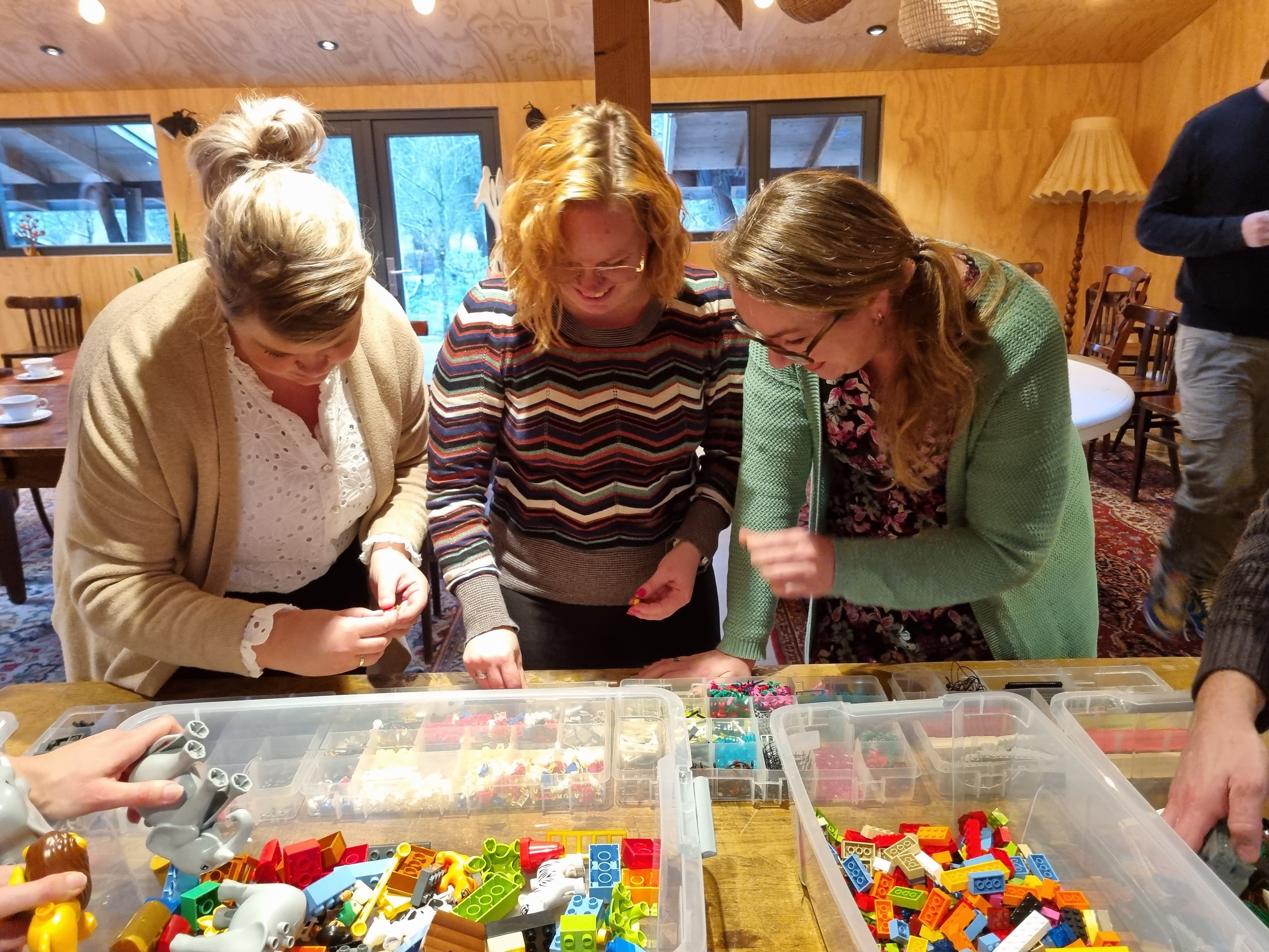 Drie deelnemers kiezen samen LEGO-stenen voor hun modellen